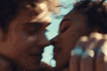 a man and a woman are kissing with their eyes closed .