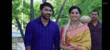 a man and a woman are standing next to each other in a park and smiling at the camera .
