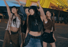 a group of young women are standing on a street with their arms up in the air