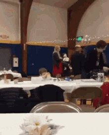 a group of people gathered around tables in a room with a green exit sign