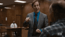 a man in a suit and tie is talking to another man in a courtroom ..