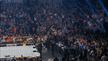 a referee stands in front of a crowd watching a wrestling match between two men