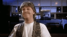 a man in a vest is making a funny face in a room .