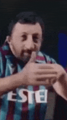 a man with a beard is giving a thumbs up while wearing a shirt that says este .