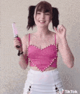 a woman in a pink top and white skirt is holding a pink wand and a tiktok logo is visible in the corner
