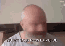 a bald man with a beard is making a funny face and says `` on est tous dans la mere '' .