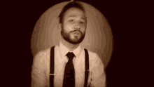 a man with a beard and suspenders is standing in front of a circle .