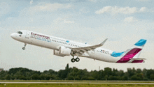 a white and purple airplane is taking off from the runway