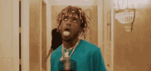 a man with dreadlocks and a blue shirt is standing in a hallway with his tongue out .