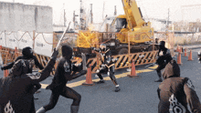 a group of people standing in front of a construction site with a yellow crane behind them