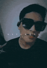a man wearing sunglasses and a black shirt looks at the camera