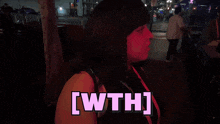 a woman stands in front of a sign that says wth
