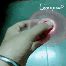a person 's hand is holding a pink object with the words emo.com written on the bottom