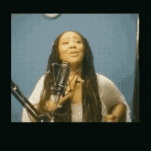 a woman with long dreadlocks is singing into a microphone .