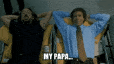 a man in a blue shirt and tie says " my papa " while laying down