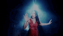 a woman in a red dress is dancing on a stage in front of a light .