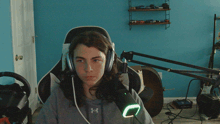 a person wearing headphones and an under armour shirt sitting in front of a microphone