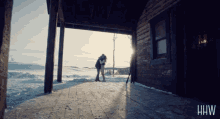 a couple hugging on the porch of a cabin with the letters hw on the bottom