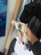 a person is holding a toy gun in front of a closet