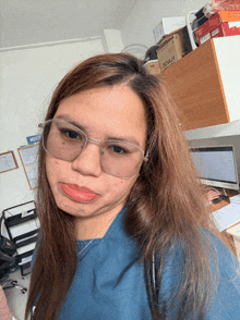 a woman wearing glasses and a blue shirt is making a funny face in front of a box that says regular