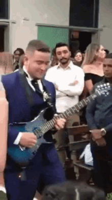 a man in a suit is playing an electric guitar in front of a crowd