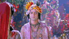 a man in a turban with a peacock feather on it is standing next to a woman .