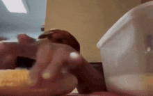 a close up of a person eating a sandwich with a plastic container in the background