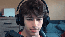 a young man wearing headphones is sitting in front of a microphone in a room .