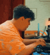 a man in an orange shirt is typing on a keyboard