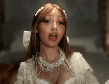 a woman wearing a white dress with pearls and a bow on her head