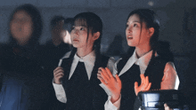two girls covering their mouths with their hands while looking at something