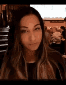 a woman is sitting at a table in a restaurant and making a funny face .
