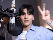 a man is giving a peace sign in front of a microphone .