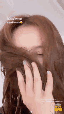 a woman covering her face with her hair with a smiley face above her