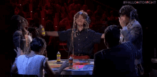 a group of people sitting around a table with a person covered in slime .