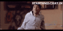 a man in a striped shirt is dancing in front of a sign that says startamilchat.in