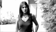a black and white photo of a woman standing in front of a house .