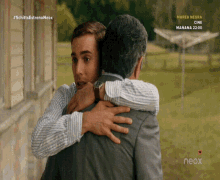 two men hugging in front of a screen that says neox