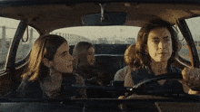 a woman is driving a car with two girls in the back