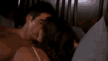 a man and a woman are laying in bed , the woman is holding the man 's arm .