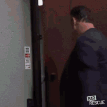 a man in a blue jacket with the word bar rescue on his back