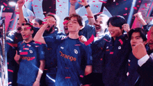 a group of people wearing orange shirts celebrate