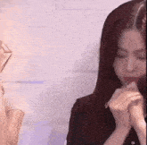 a woman is sitting in front of a microphone with her hands folded .