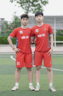 two soccer players wearing red uniforms with the number 25 on their shorts