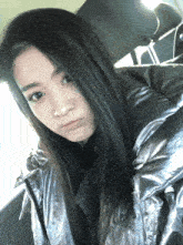 a woman wearing a silver jacket looks at the camera