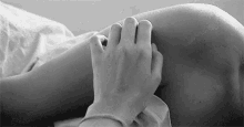 a black and white photo of a person 's hand on another person 's knee .