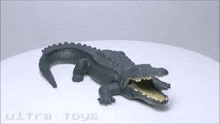 a toy crocodile with its mouth open is sitting on a white surface