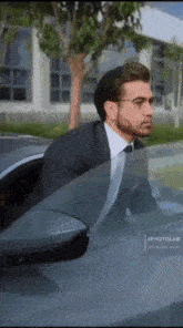 a man in a suit and tie is getting out of a car window .