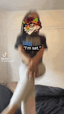 a woman is sitting on a couch with a fox face on her shirt that says i 'm sat