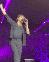 a man is singing into a microphone on a stage